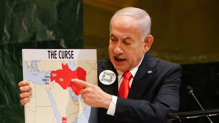 Netanyahu wearing a QR code pin while referencing a graphic labeled “The Curse” during his UNGA speech.