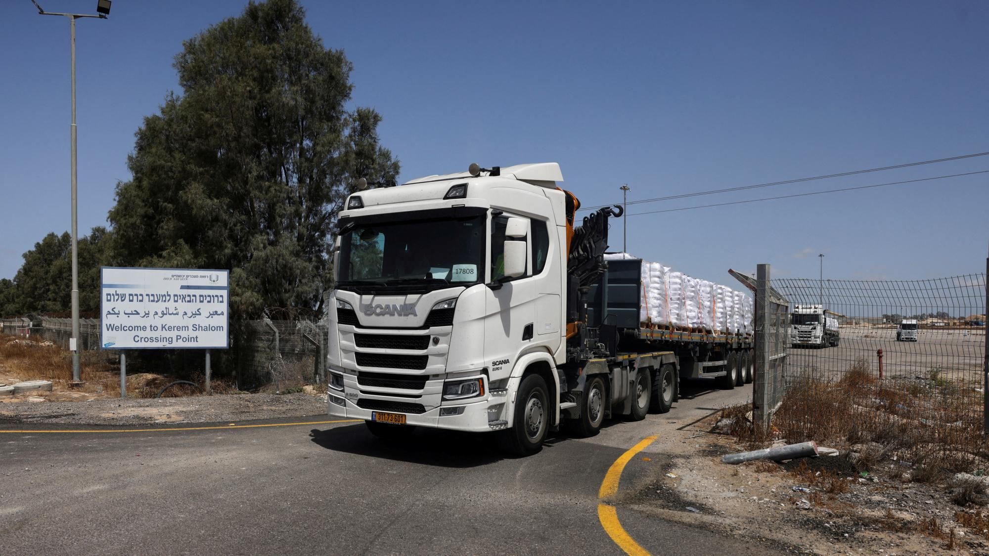 Border inspection lanes with posted hours and signage as trucks line up for checks