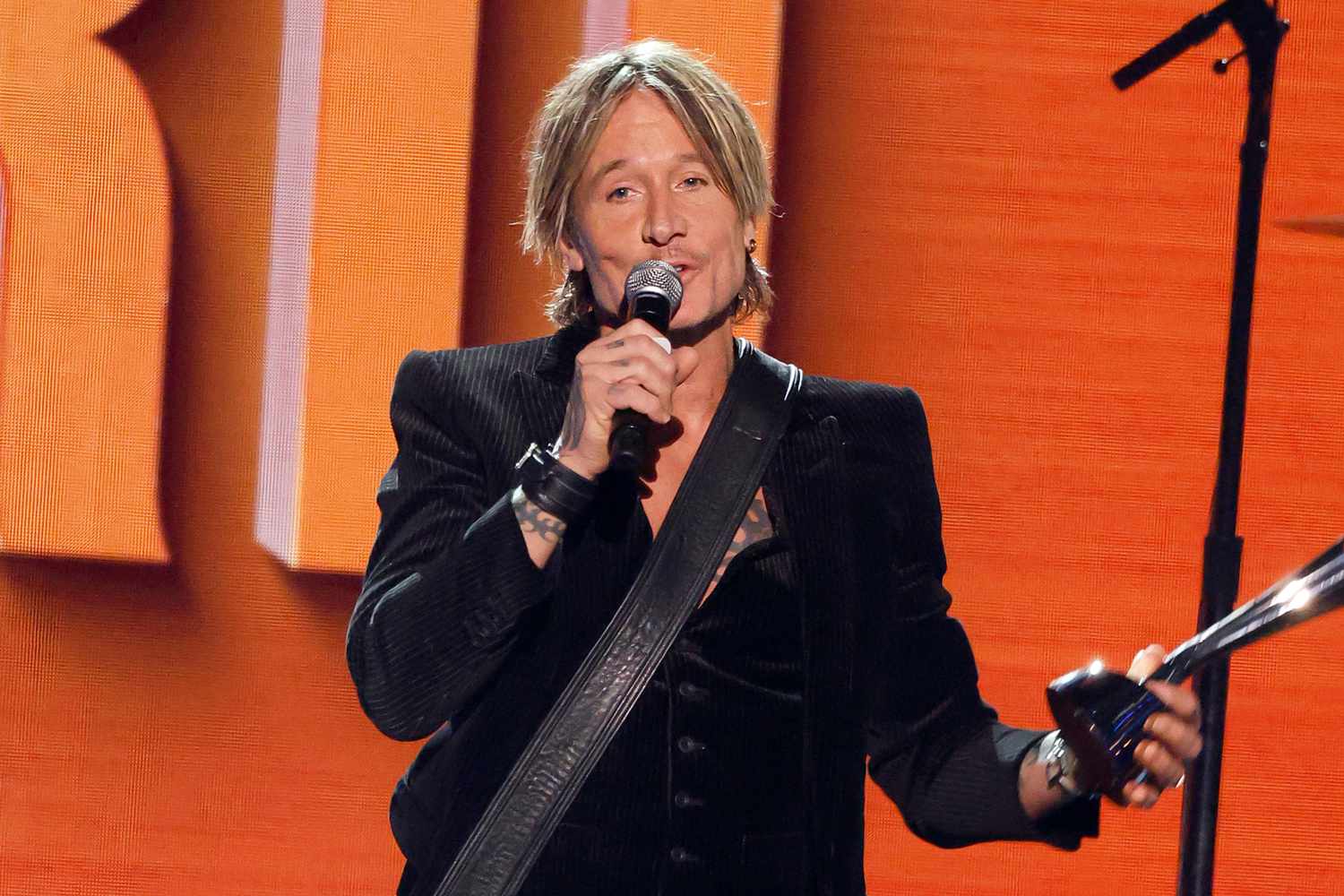 Keith Urban smiling on a red carpet before a performance, guitar focused career image