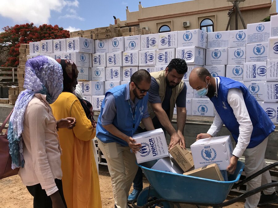 Humanitarian workers distributing food and water in refugee camp near El Fasher