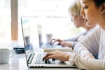 Students working in a modern workspace as the return on investment of college tuition is compared with on-the-job training and trade schools in 2026