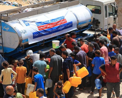 Civilians gather near aid trucks in Gaza amid humanitarian crisis and ongoing conflict