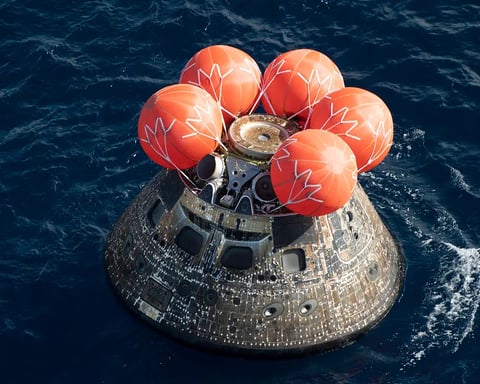 Orion spacecraft floating in the Pacific Ocean after Artemis II lunar mission splashdown with NASA recovery teams nearby