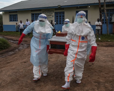 Medical staff in PPE carry a patient at an Ebola treatment centre in DRC's Ituri province, 2026